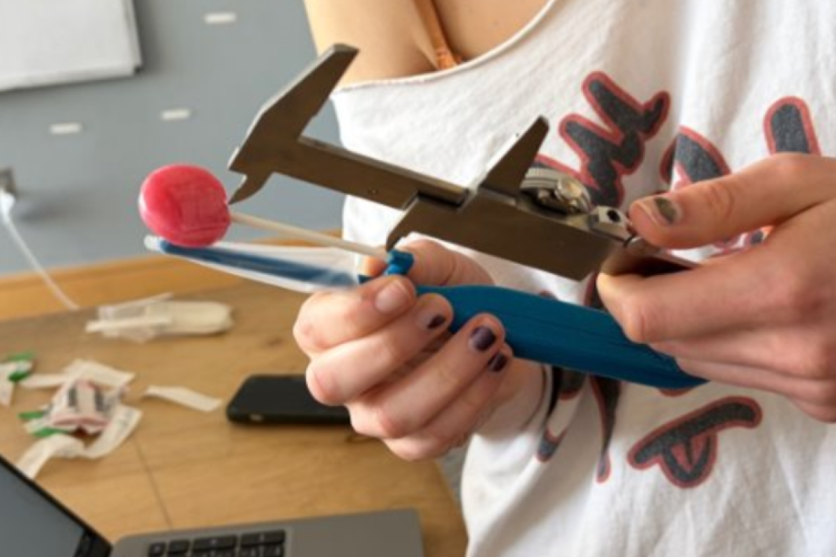 A student in Olin's Biomedical Device Design course is pictured using a caliper to measure a prototype medical device.