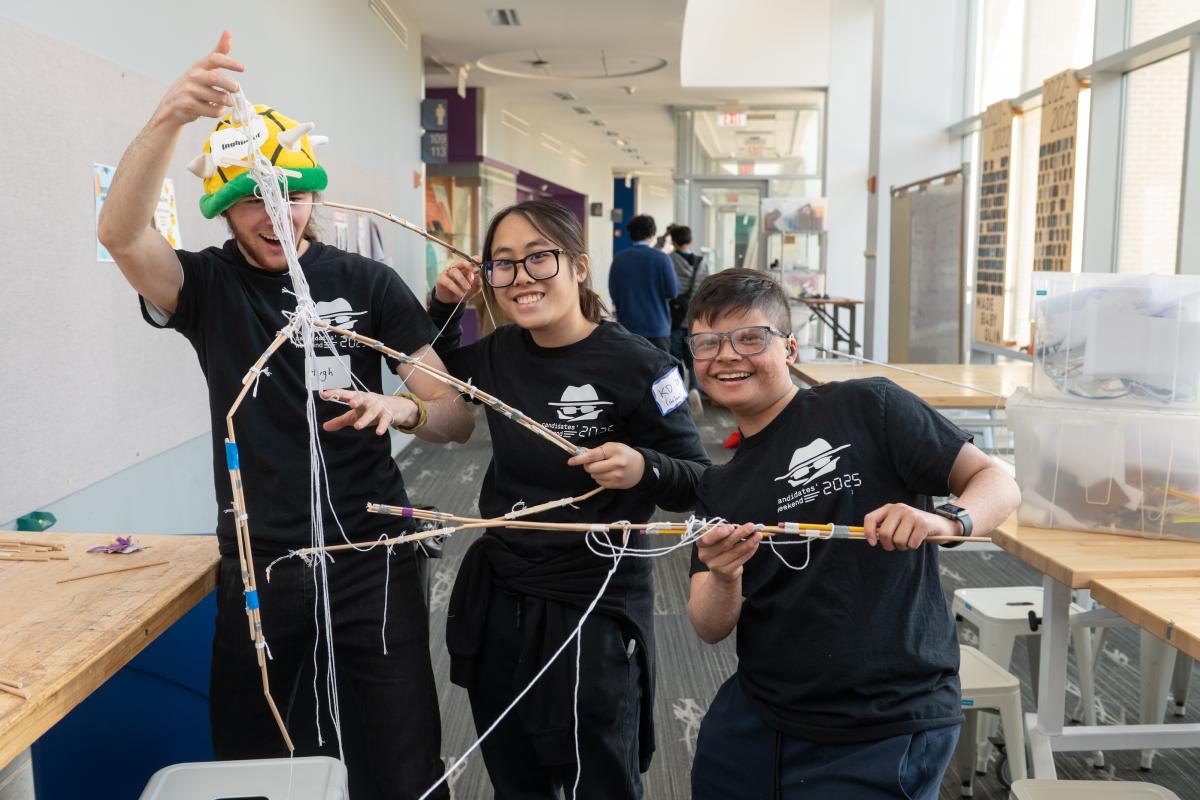 Three Olin College of Engineering students display part of an engineering build challenge. 