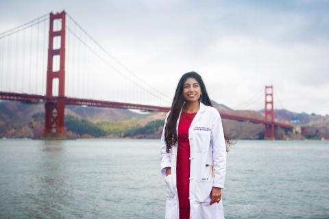 A photo of a young woman standing by the water with the Golden Gate Bridge in the background.