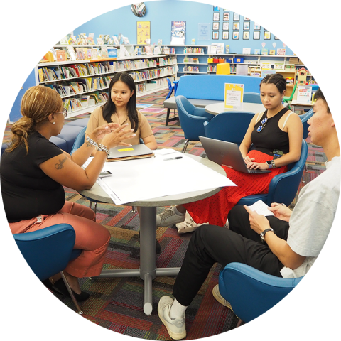 Students discuss a project surrounding a table