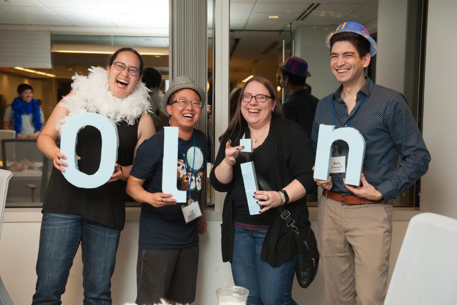 A group of four people holding letters that spell Olin