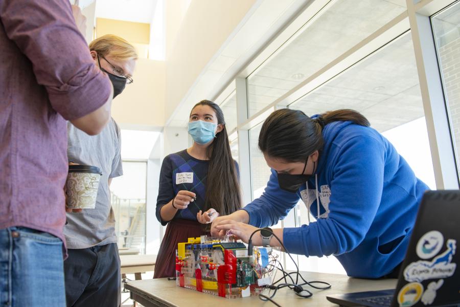 Two students share their project with two visitors to their table during Fall 2021 Expo.