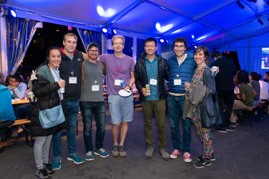 A group of people standing arm in arm and smiling at the camera