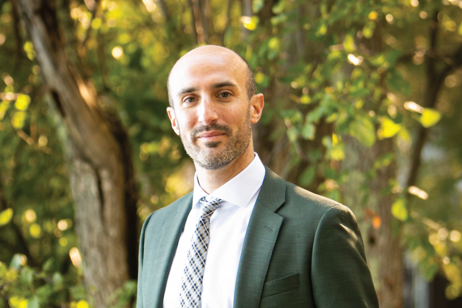 Daniel Koff portrait, surrounded by trees in a green suit