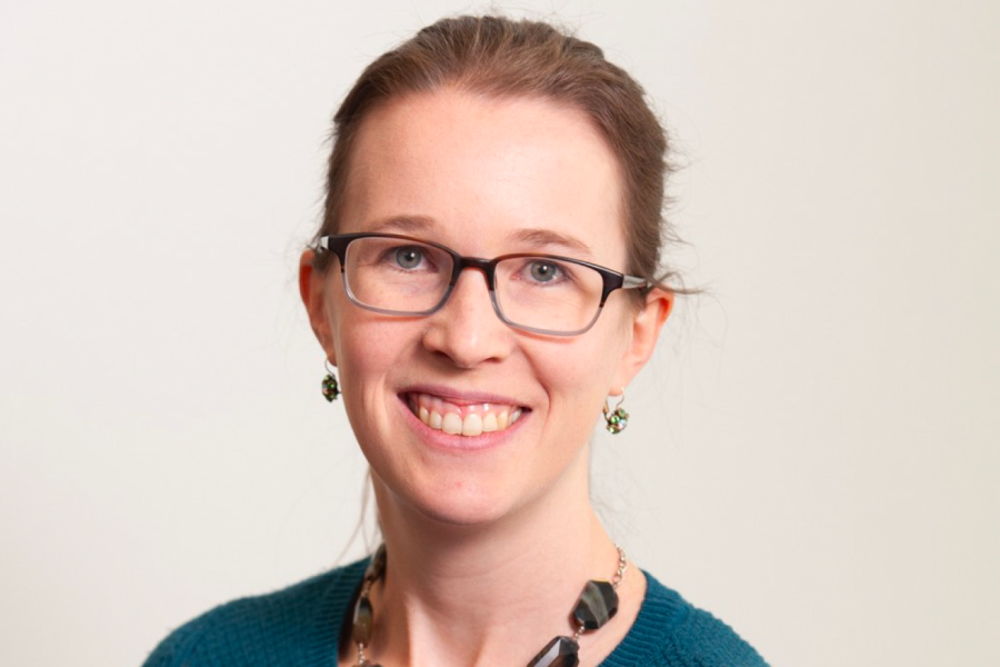 Emily Tow Headshot - Brown-blonde ponytail, glasses, smiling at camera