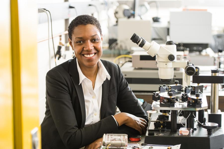 Dr. Shayla Sawyer Armand Sitting next to a Microscope