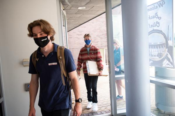 A photo of two young people walking into a building on their first day of college