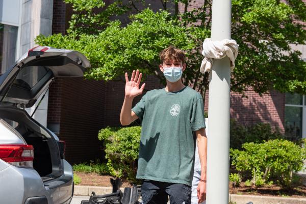 A photo of a person standing outside and waving