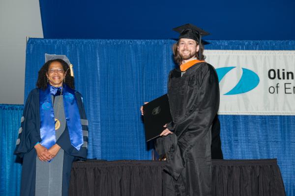 President Barabino on stage during Commencement with a new graduate