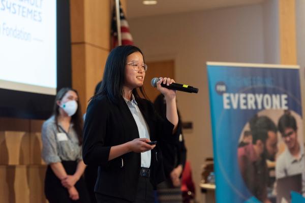 A student holds a mic while presenting a project in the Norden Auditorium during SCOPE Summit 2022.