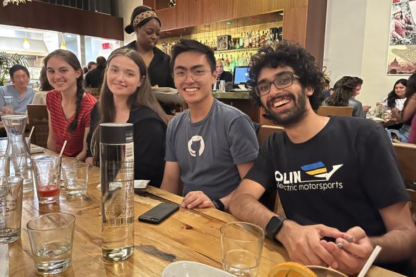 Four people smile while sitting next to each other at a table.