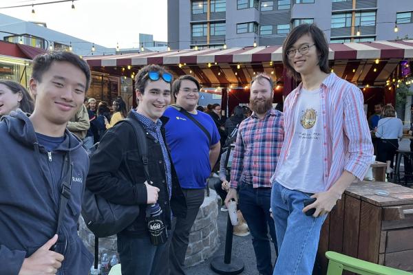 Five people pose together outside at an event.