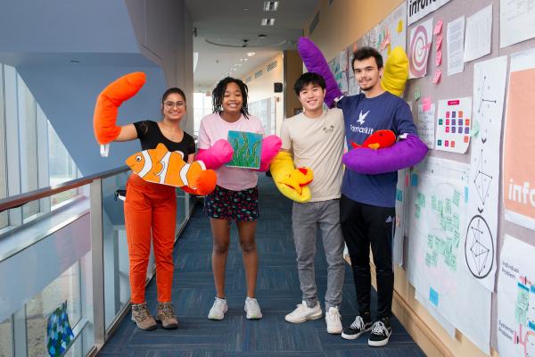 Four students stand in a row with brightly-colored "claws" on their hands.