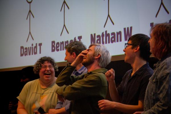 A student holds his hand to his head while laughing during an Olin student ceremony.