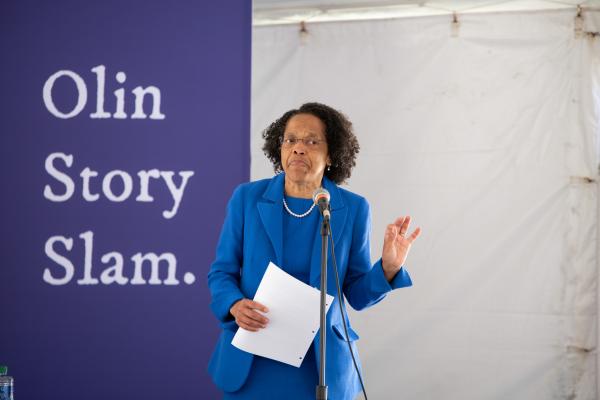 A woman stands in front a sign that reads Olin Story Slam