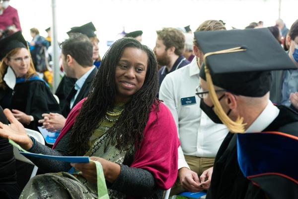 A woman is seating and talking to the person sitting next to her