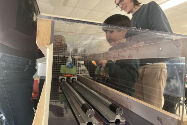 Van Myers '24 observes while a young student tries out the Wind tunnel Workshop