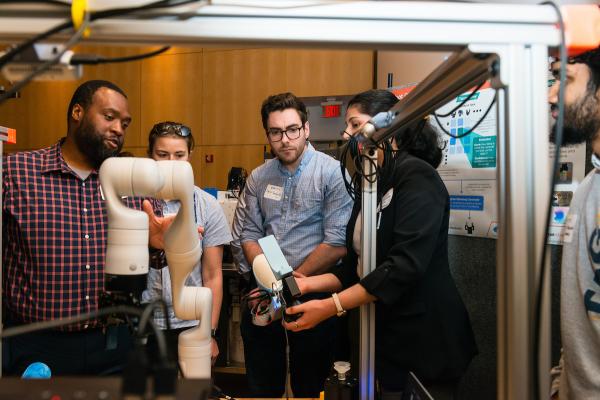 Students demonstrating their project that uses a robotic arm to a SCOPE Summit visitor.