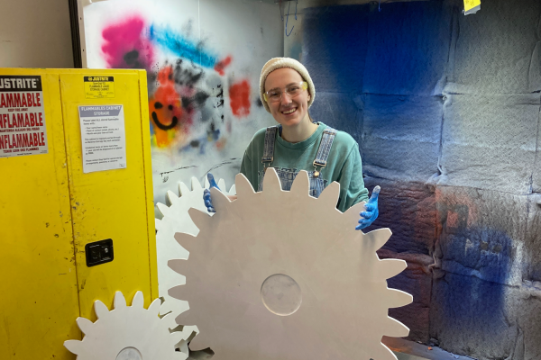 Maya McKone-Sweet in Large Project Building (LPB) holding gear. 