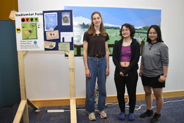 Three students stand with their final project. 