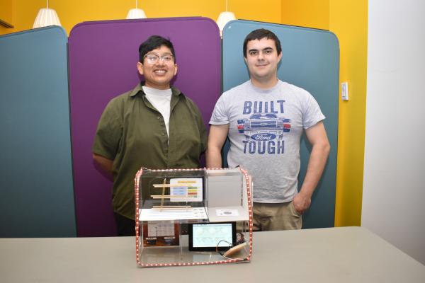 Two students stand with their final project. 