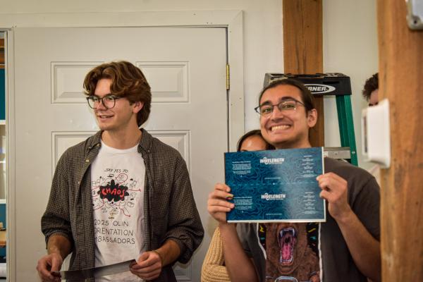 Students are listening to Jim Varney speak about Wavelength. The student on the right holds up Wavelength's can labels. 