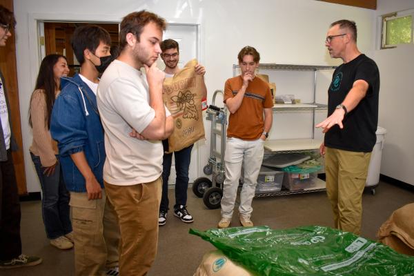Students standing around a bag of coffee beans as they learn about Wavelength's sourcing.