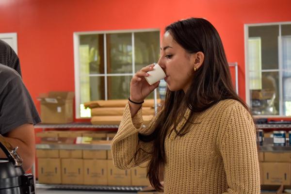 A student drinks coffee a sample-sized cup.