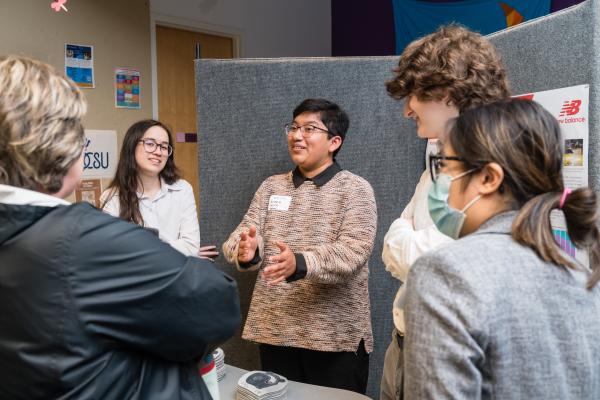 Students presenting in front of project poster at Summit