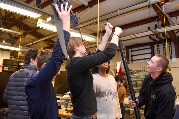 Five Olin OCTAL project team members work together to feed wires into a tube.