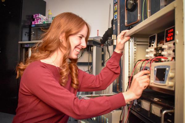 An Olin OPEL project team member smiles and adjusts equipment on a shelf.