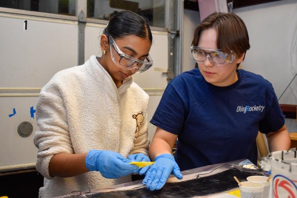 Two Olin Rocketry project team members work together at a workbench in the LPB.