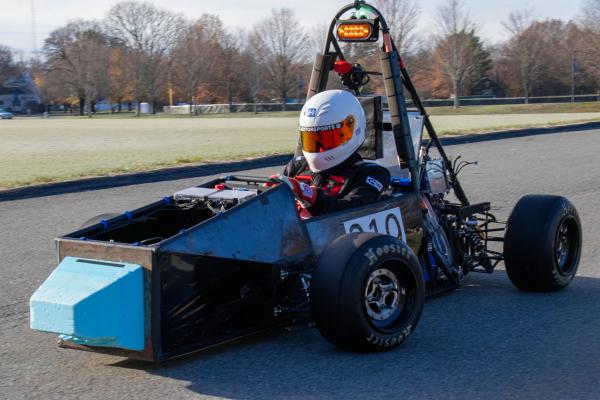 An Olin OEM member sits in the race car built by the team. 