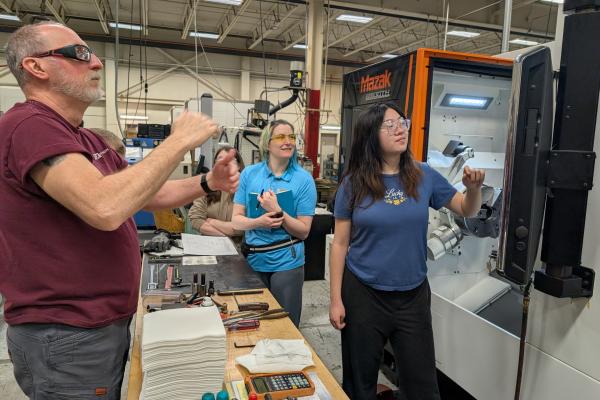A student and staff member learn about the manufacturing process at Instron. 