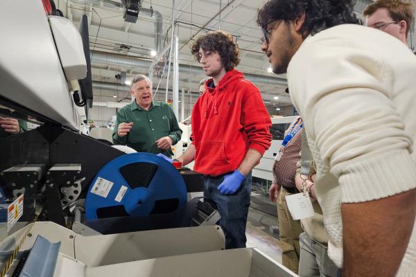 Students observe a team member operating a machine at Z-AXIS/Bear Power Supplies.