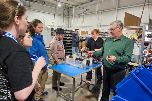 Students gather around a Z-AXIS/Bear Power Supplies Facility Tour presenting information. 