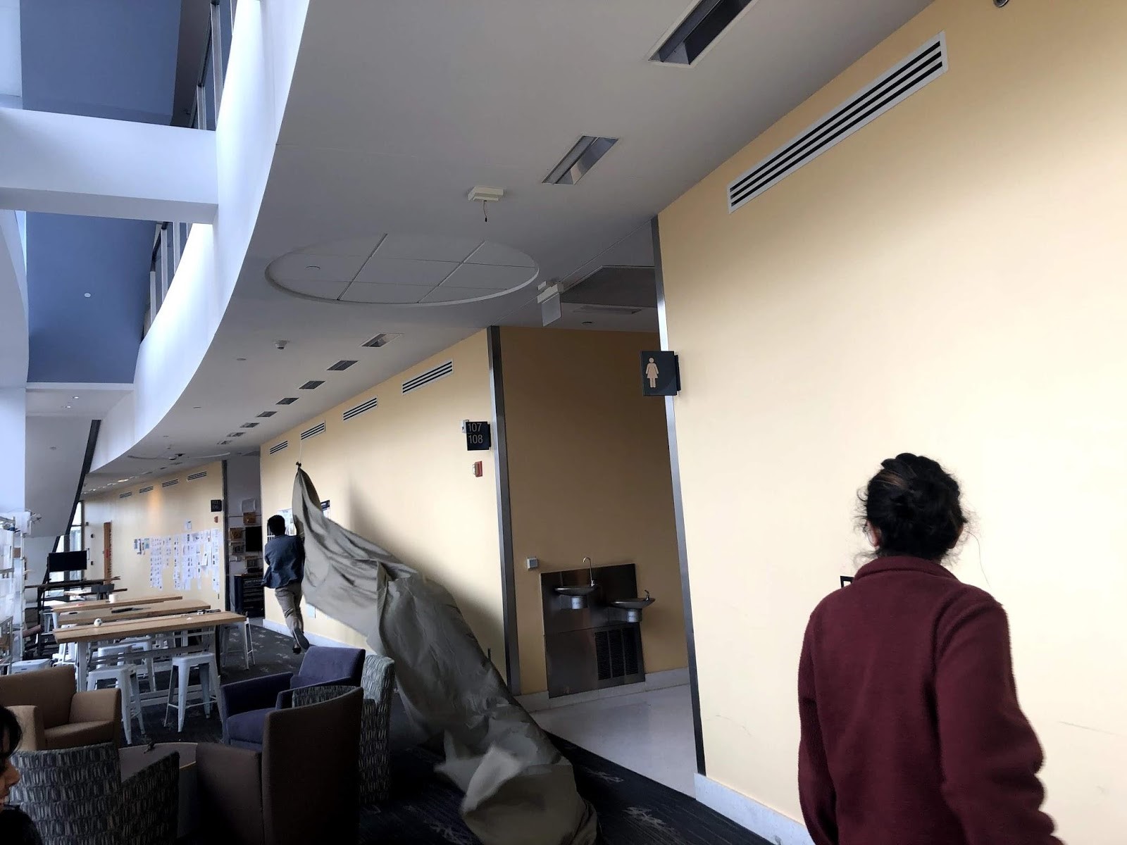 A hallway with tables, stools, and chairs.